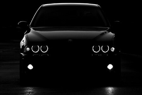 Чёрная машина на чёрном фоне, включены только фары Ангельские глазки.
