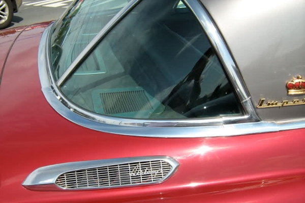 Задняя полка автомобиля Chrysler Imperial красного цвета. На ней — хромированное вентиляционное отверстие.